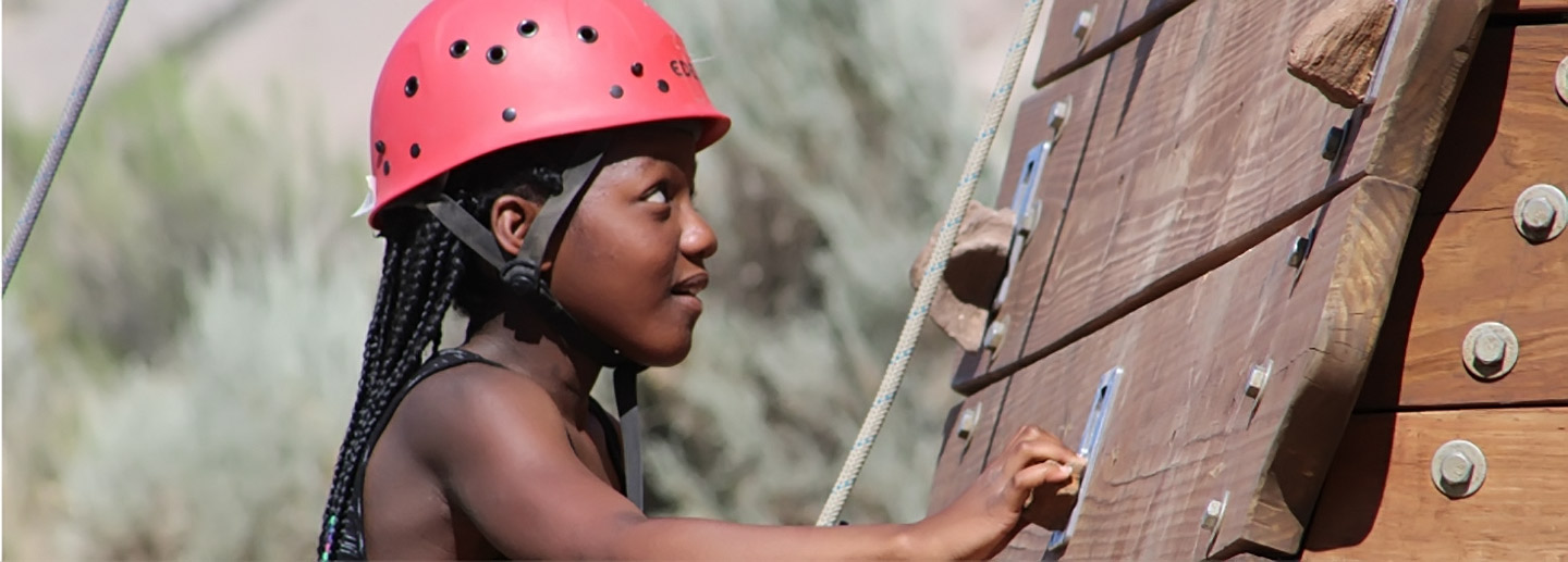 A camper scales a climbing wall at Colorado nonprofit summer camp