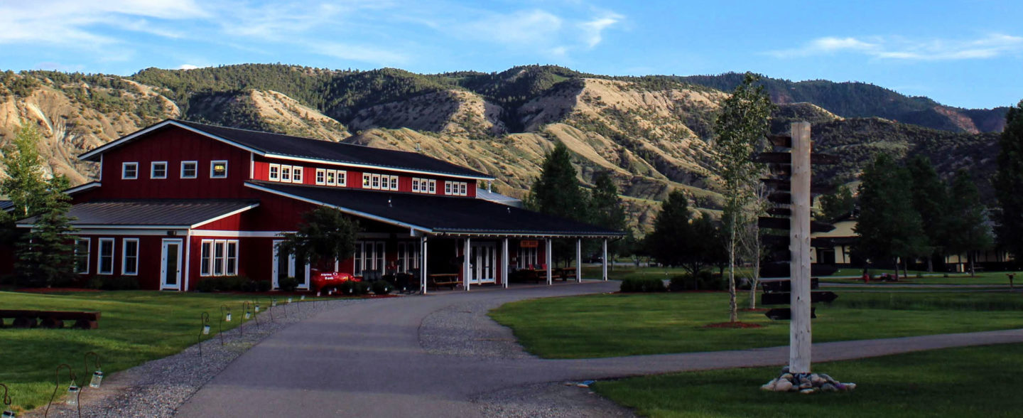 Big red ranch house in front of the mountains at nonprofit Colorado River ranch camp for youth
