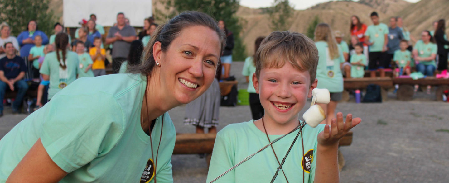 Summer camp counselor and child roasting marshmallows at Colorado River Ranch camp