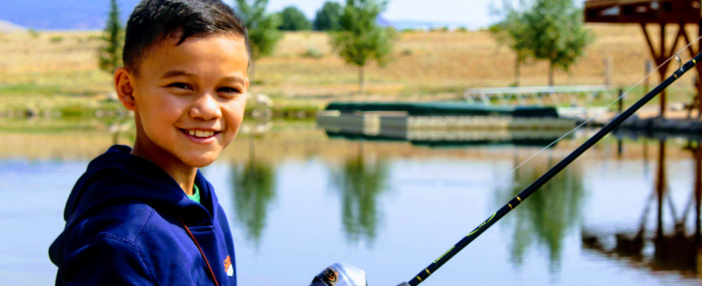 A child holding a fishing rod at Colorado River ranch summer camp in Colorado