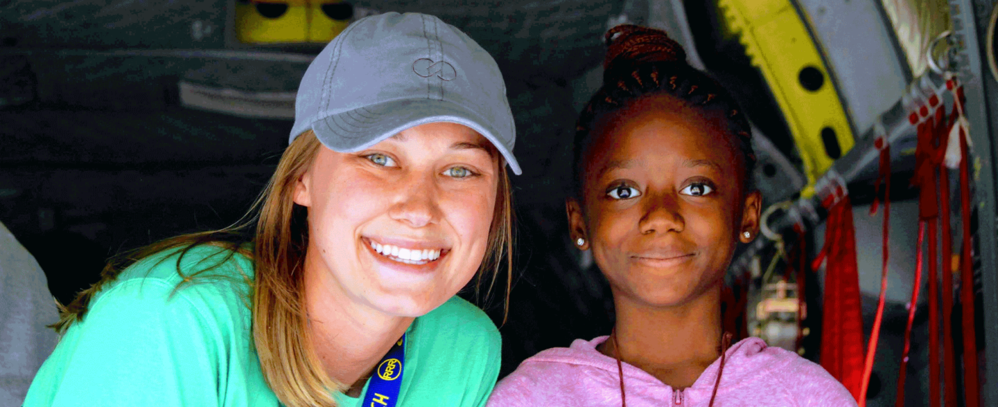 A young camper and a volunteer smile for a photo. Explore volunteer opportunities to give back with Roundup River Ranch.