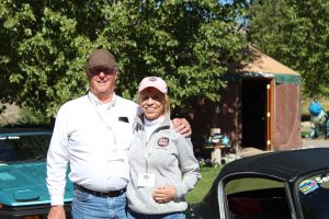 Ann and Ross stand next to their car.