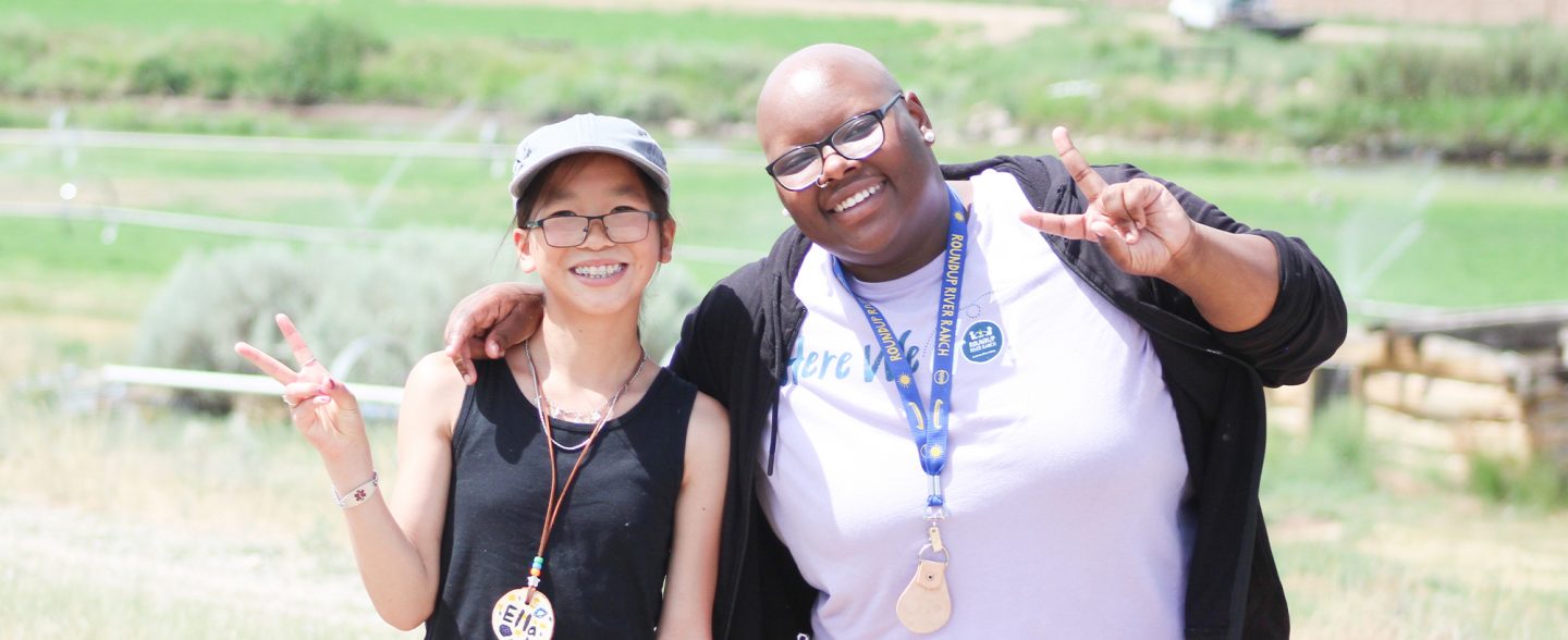 A camp volunteer and camp attendee pose for a candid photo. Apply to be a volunteer at Roundup River Ranch.