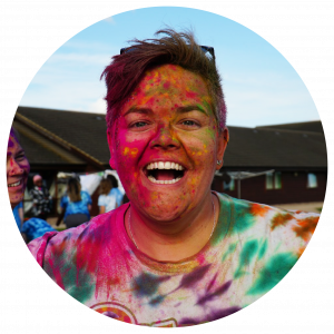 RED, our Camp Director, covered in colorful paint with a wide grin on her face.